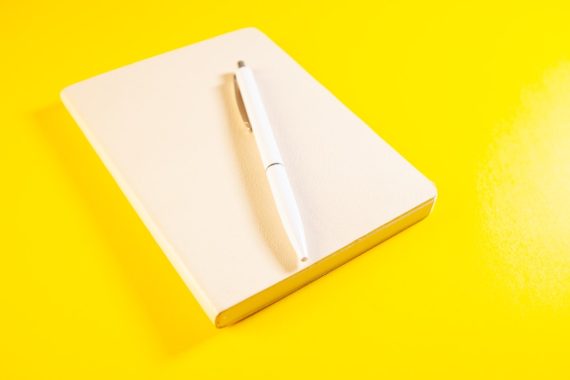 Notebook and pen on yellow background. Business and office concept.