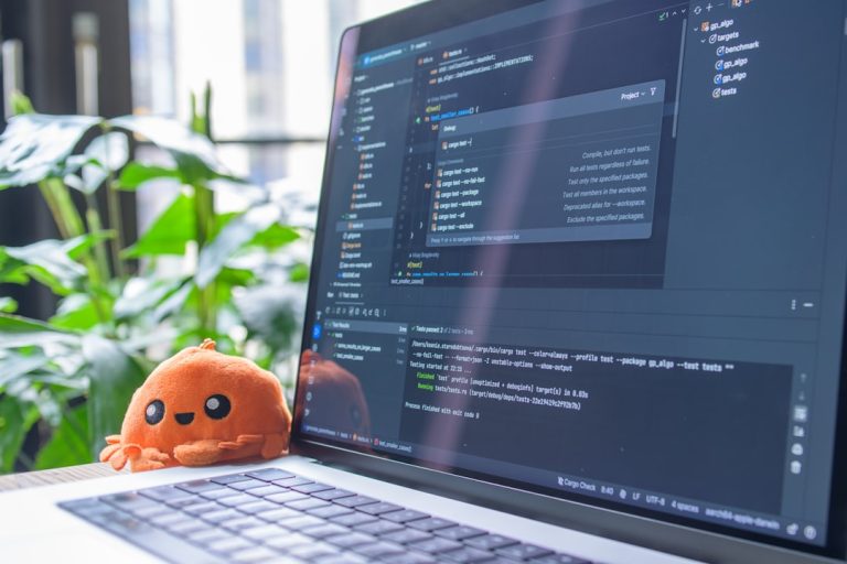 Laptop screen displaying code with a small plush toy.