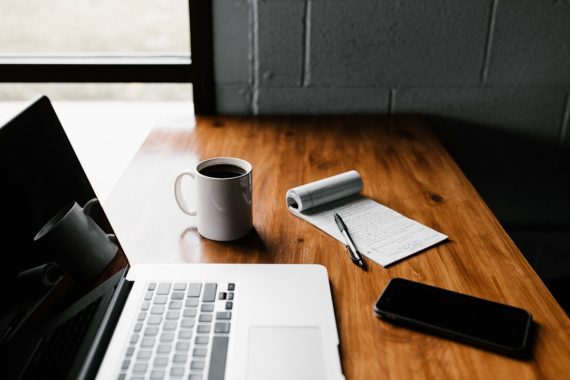 Laptop and notebook on a desk during a website platform decision