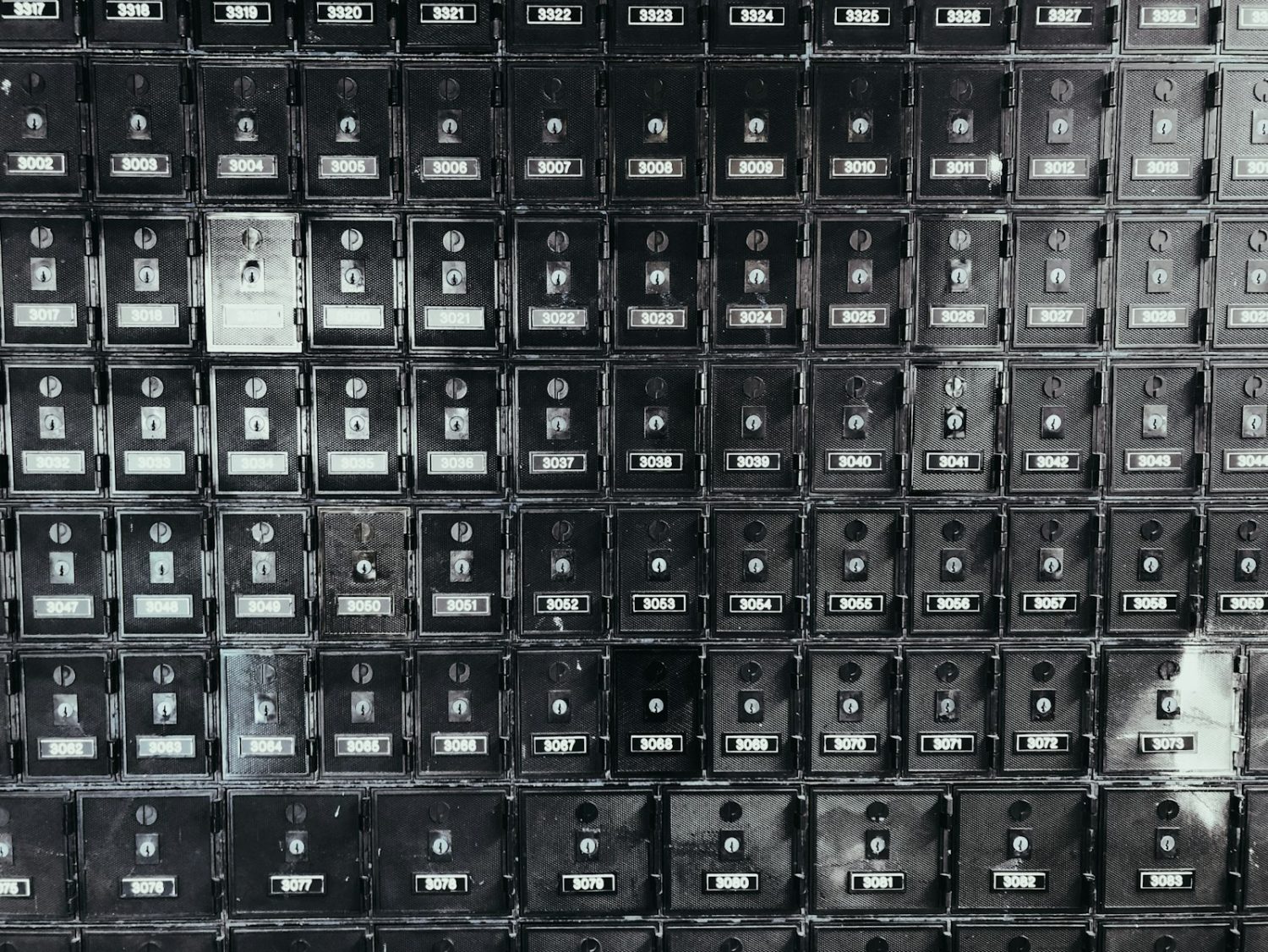 A grid of old metal post office boxes with brass doors