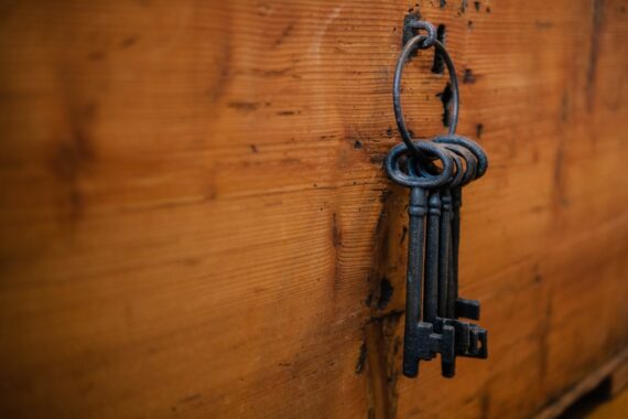 A ring of old iron skeleton keys hanging from a nail on a weathered wooden wall