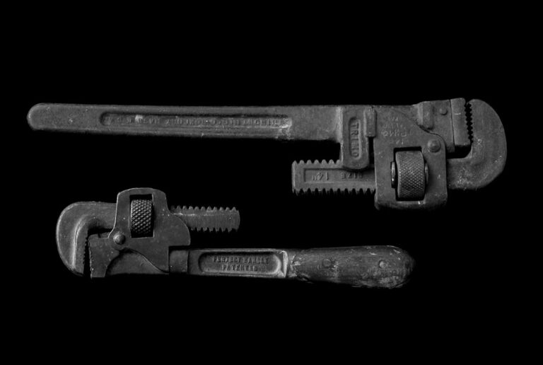 Two pipe wrenches of different sizes photographed against a black background