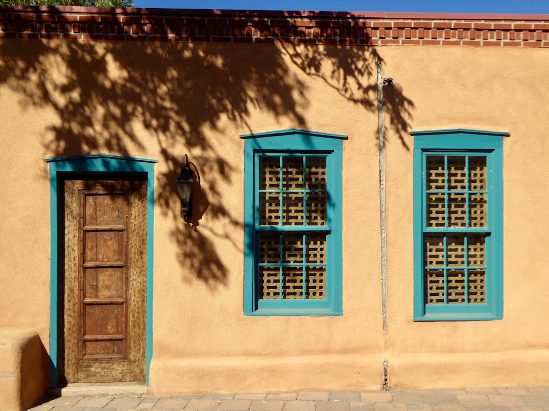 Adobe building with turquoise-painted window frames and door in Santa Fe, New Mexico