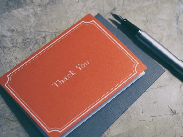 Handwritten thank-you note and pen on a wooden desk